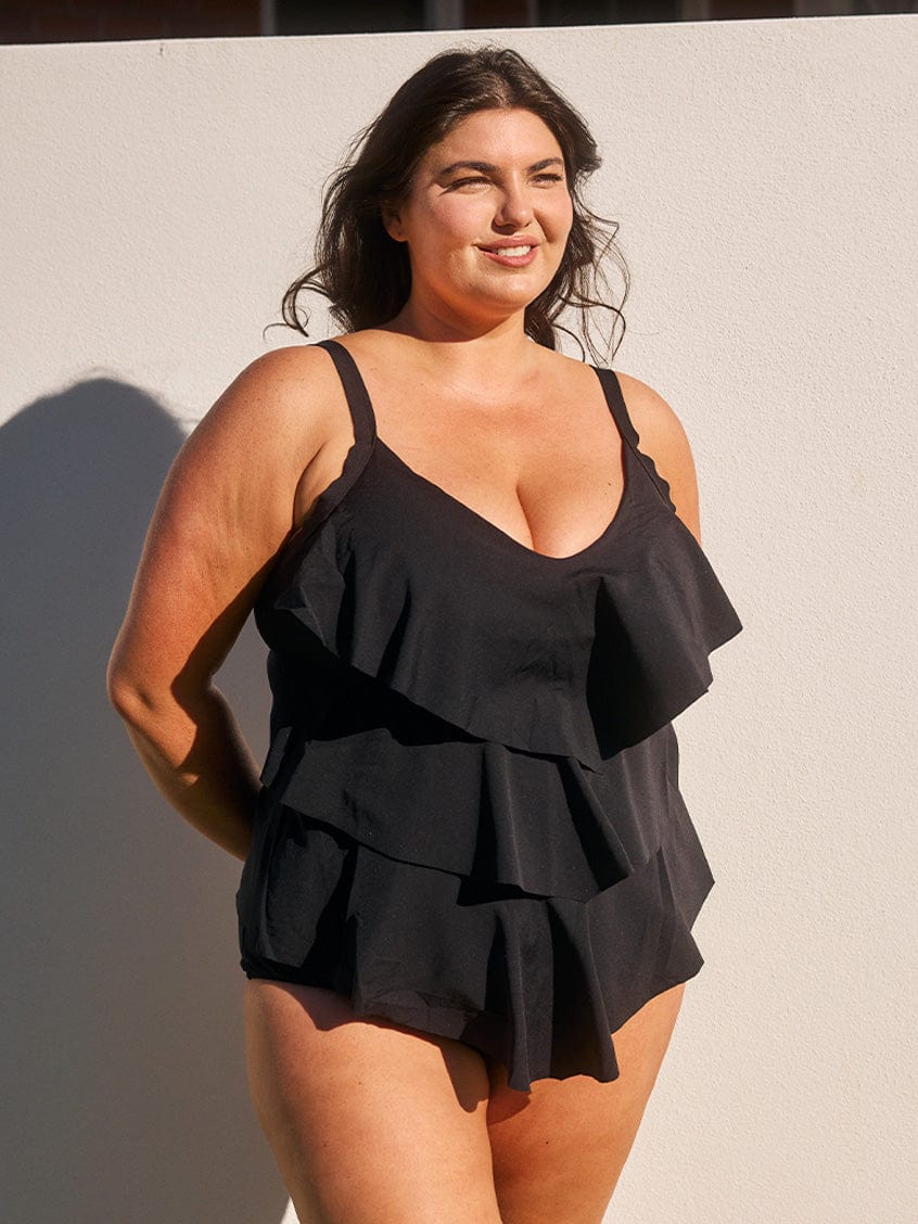 Woman wearing a black ruffled dress against a neutral background