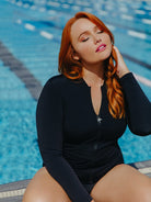 Woman in a black swimsuit sitting by a pool