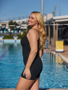 side profile of girl standing in front of a pool wearing a black swimsuit