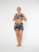 Woman wearing a black floral sports bra and shorts set on a white background