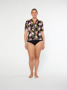 Woman wearing a floral short-sleeve swimsuit on a white background