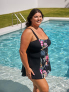 Woman in a black floral dress standing by a pool