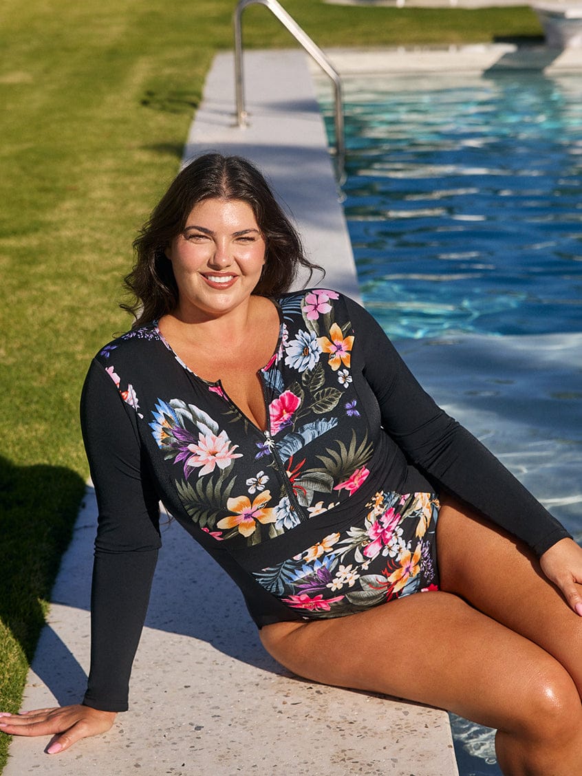 Woman in a floral swimsuit sitting by a pool