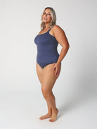 Woman wearing a blue polka dot swimsuit on a white background