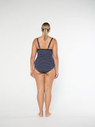 Woman wearing a navy patterned swimsuit on a white background