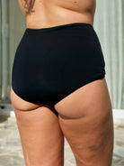 Back of model wearing a full coverage high waisted black swim pant with chlorine resistant fabric