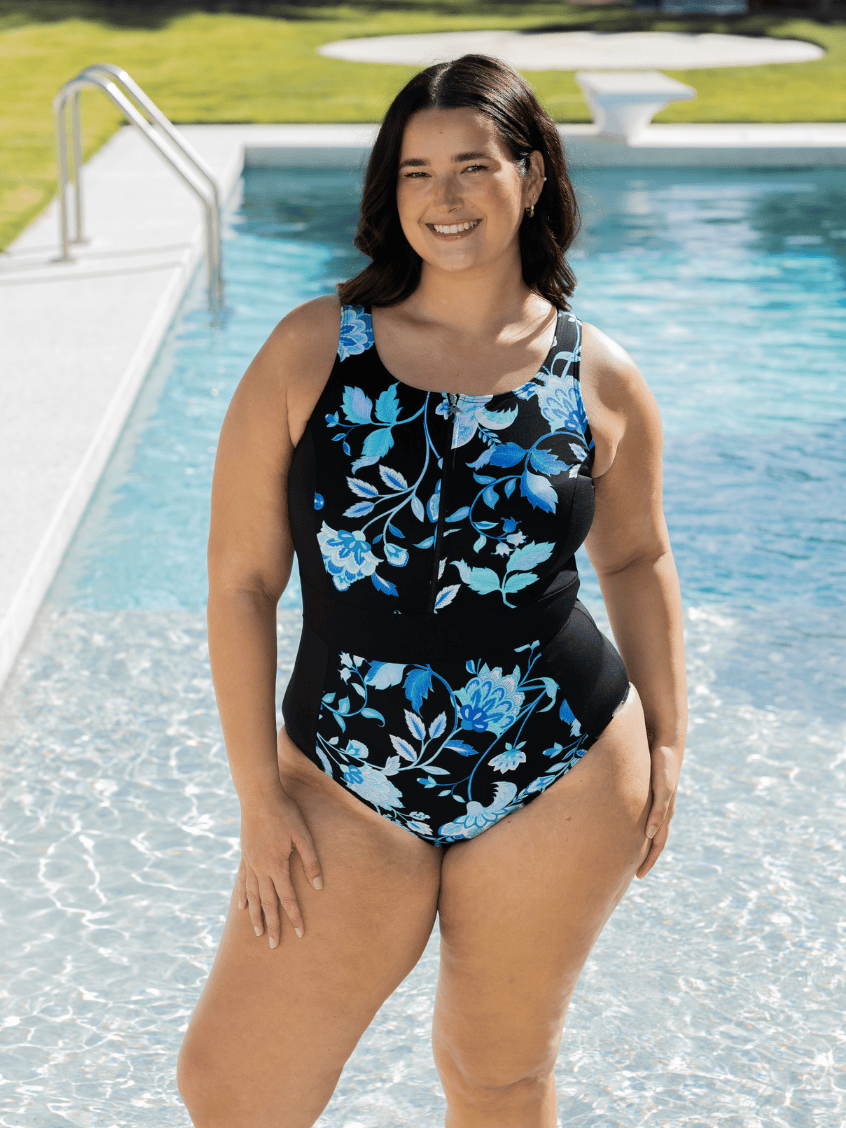 Woman wearing a black floral swimsuit by a pool in chlorine resistant