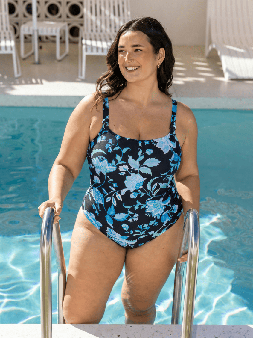 Woman in a floral swimsuit standing by a pool