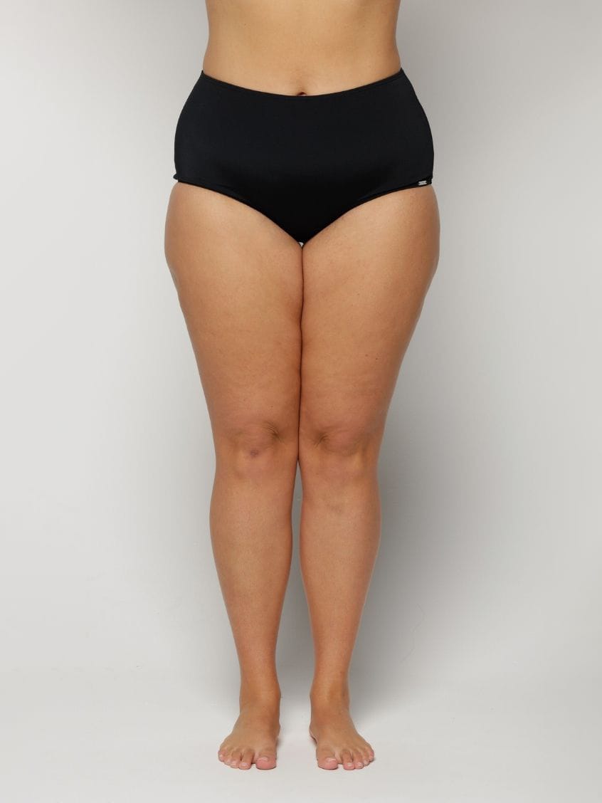 Woman wearing black high-waisted underwear on a plain background