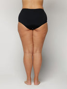 Woman wearing black high-waisted underwear on a plain background