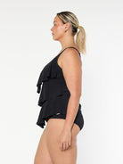Blonde model wears black 3 tier ruffle tankini top in chlorine resistant fabric