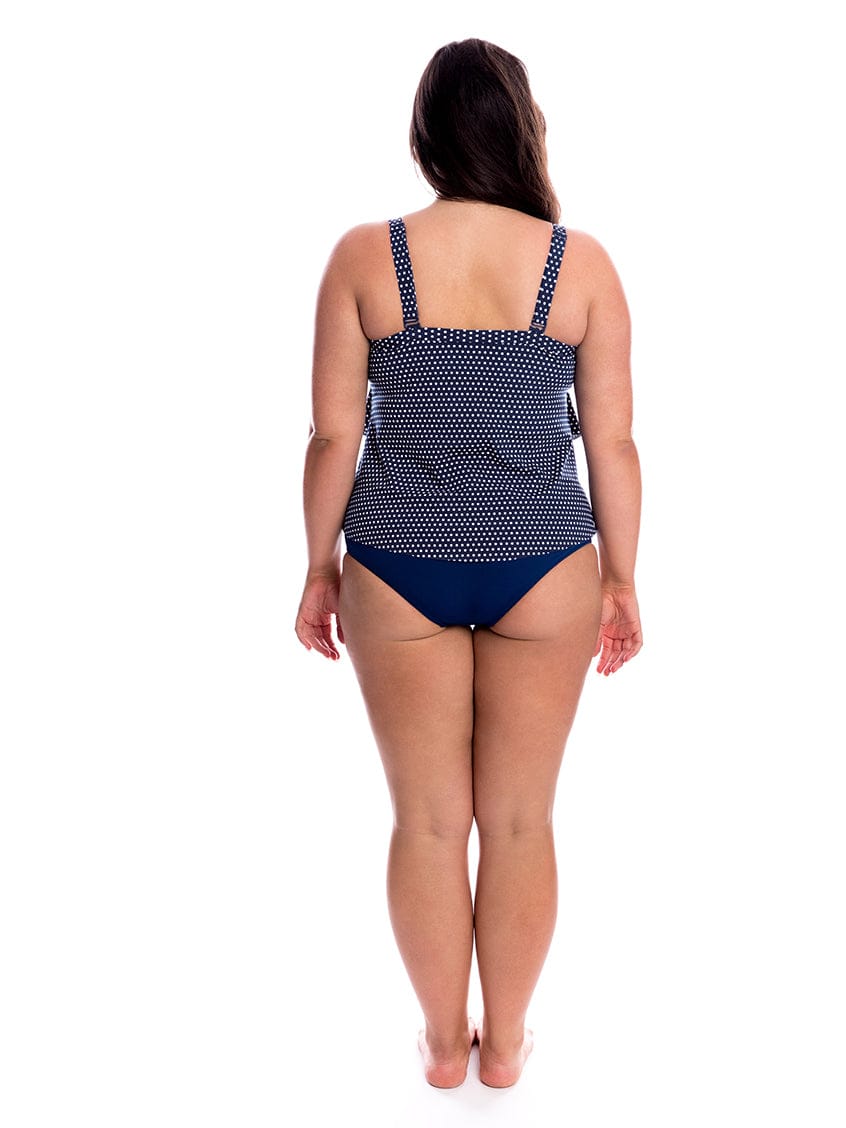 Woman wearing a navy polka dot swimsuit on a white background