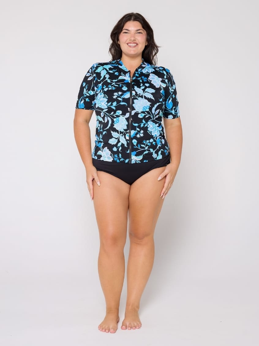 Woman wearing a black floral shirt and black swimsuit on a white background