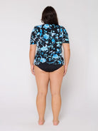 Woman wearing a black swimsuit with blue floral patterns on a white background