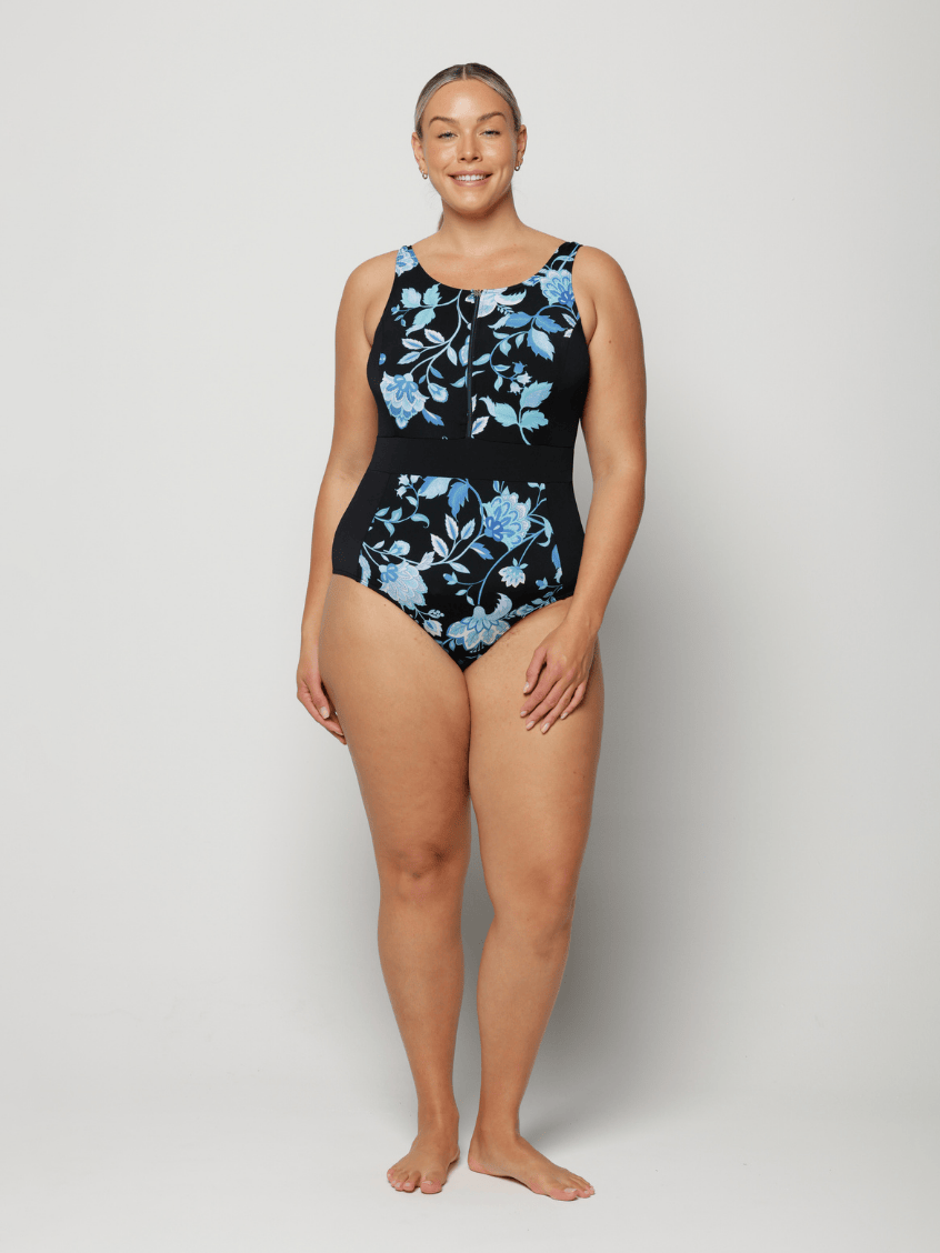 Woman wearing a black one-piece swimsuit with blue floral patterns on a white background