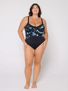 Woman wearing a black one-piece swimsuit with blue fish pattern on a white background