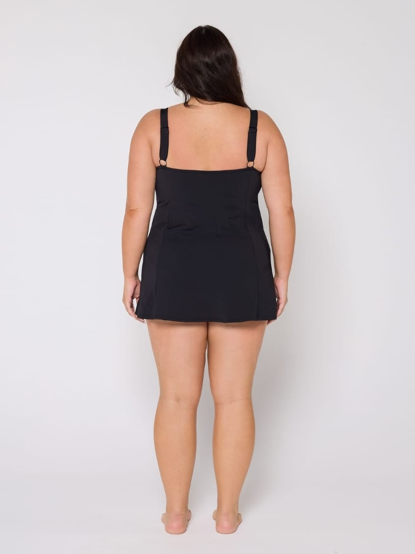 Woman wearing a black slip dress against a white background