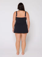 Woman wearing a black slip dress against a white background