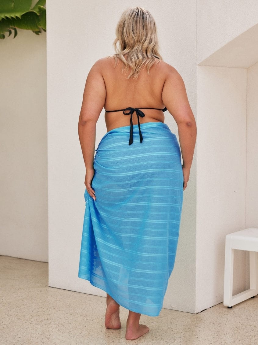 Woman wearing a blue striped sarong in an indoor setting