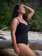 Model wearing black slimming criss cross one piece bathing suit
