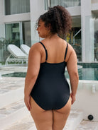 Back of model wearing a criss cross metallic black one piece with adjustable straps