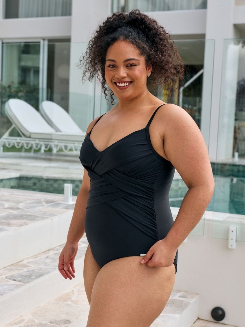 Brunette women wearing a criss cross one piece with shiny criss cross detail