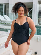 Brunette woman wearing a metallic black one piece with criss cross detail