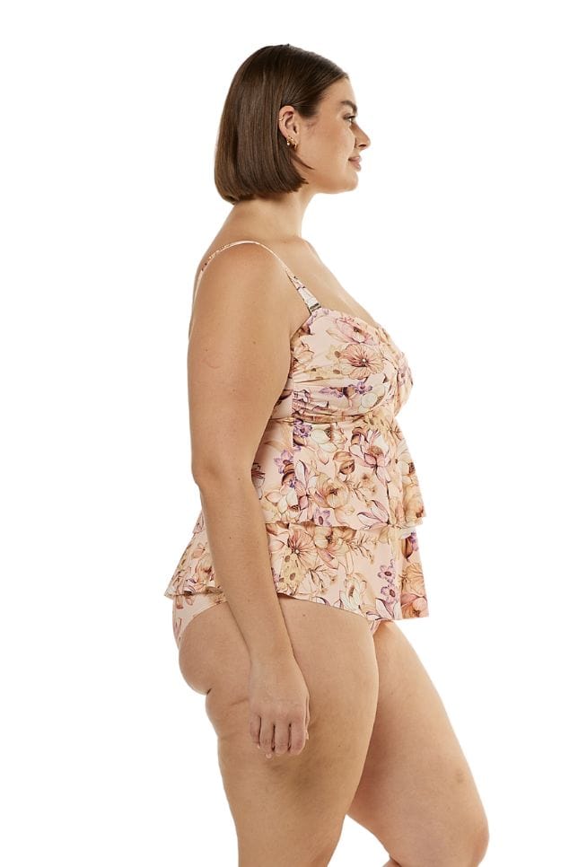 side profile of brunette model wearing soft peach floral tankini top with 2 tiers and removable straps