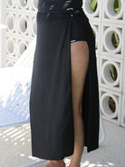 lady standing in front of a white walling wearing a long split swim skirt in black 