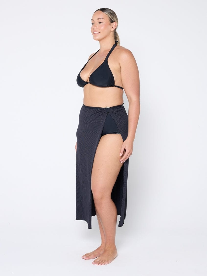 Woman wearing a black bikini and matching sarong on a white background