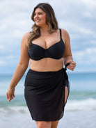 Woman wearing a black bikini and sarong on a beach