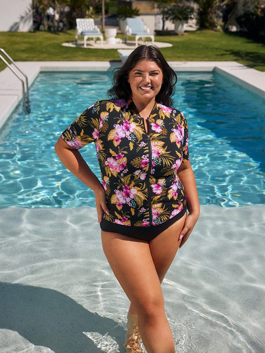 Woman in a floral swimsuit standing by a pool