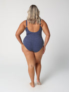Person wearing a navy polka dot swimsuit on a white background