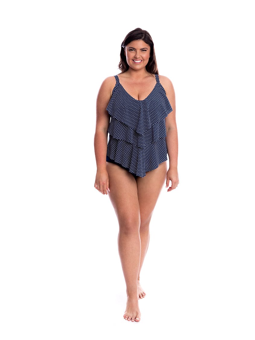 Woman wearing a navy blue polka dot swimsuit on a white background