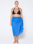 Woman wearing a black bikini and blue sarong on a white background