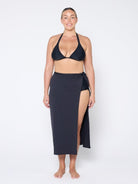 Woman wearing a black bikini and matching sarong on a white background