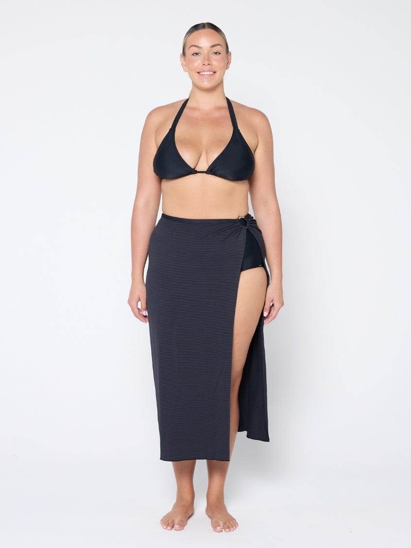 Woman wearing a black bikini and matching sarong on a white background