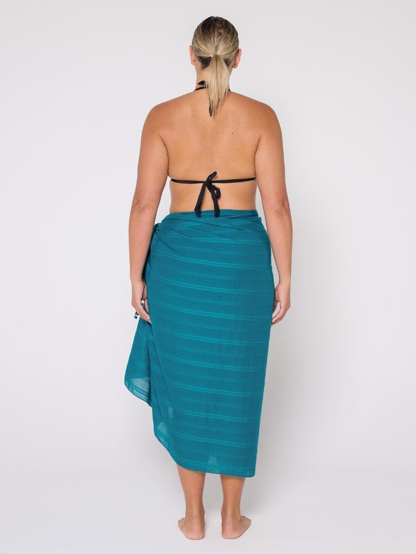 Woman wearing a teal sarong on a white background