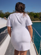 Person wearing a white t-shirt dress on a boat with a scenic background