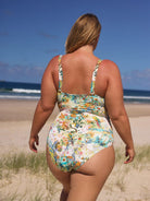 Woman wearing a floral swimsuit on a beach with ocean view
