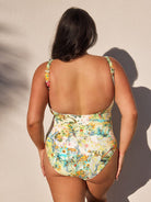 Woman wearing a floral swimsuit against a neutral background