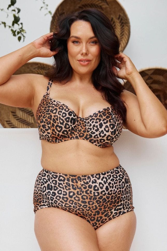 Dark haired woman wears a leopard print bikini top. The bikini top is shaped like a traditional bra with underwire and is styled with matching bikini bottoms.