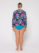 Person wearing a colorful tropical patterned shirt and blue shorts on a white background