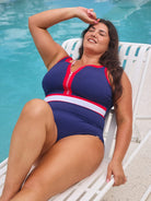 model lounging by the pool in navy and red accented sleeveless zip up one piece