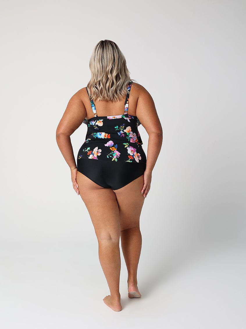Woman wearing a black floral one-piece swimsuit on a white background