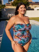 Side profile of brunette model wearing a strapless bandeau one peice with multi coloured floral print