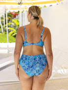 Woman wearing a blue patterned bikini set with a blurred outdoor background