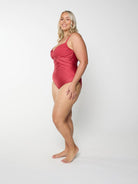 Blonde model in studio wearing a metallic red one piece with adjustble straps and ruching