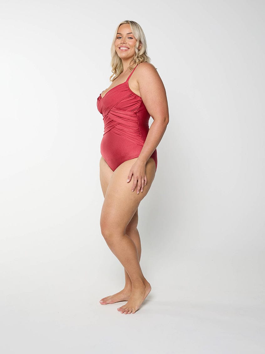 Blonde model in studio wearing a metallic red one piece with adjustble straps and ruching