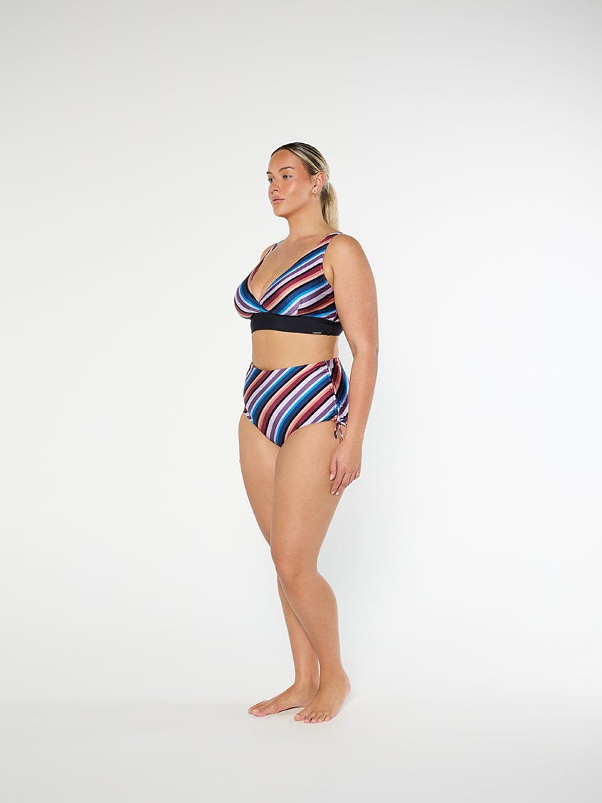 Woman wearing a colorful striped bikini set on a white background